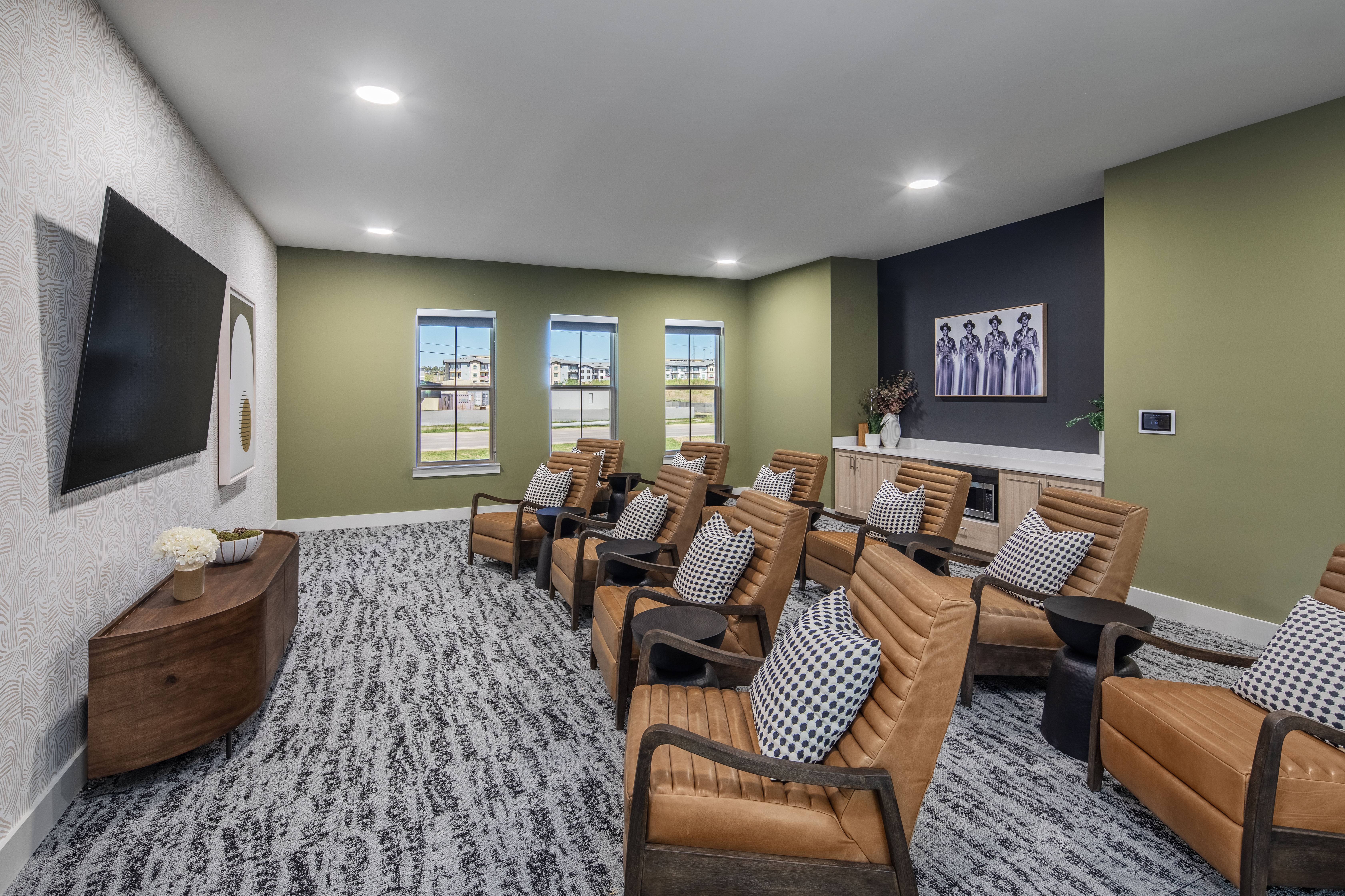 a large screening room with leather chairs and a wall mounted tv at a senior apartment community